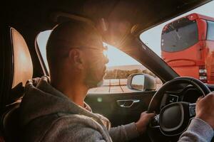 un' uomo con un' occhiali da sole guida un' auto a tramonto. il concetto di auto viaggio foto