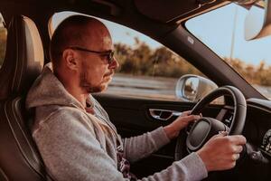 un' uomo con un' occhiali da sole guida un' auto a tramonto. il concetto di auto viaggio foto