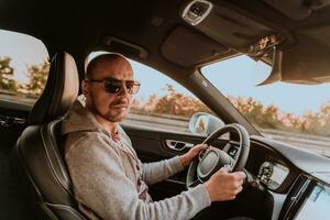 un' uomo con un' occhiali da sole guida un' auto a tramonto. il concetto di auto viaggio foto