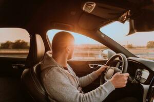 un' uomo con un' occhiali da sole guida un' auto a tramonto. il concetto di auto viaggio foto