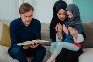 contento musulmano famiglia godendo il santo mese di Ramadan mentre preghiere e lettura il Corano insieme nel un' moderno casa foto