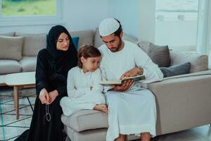 contento musulmano famiglia godendo il santo mese di Ramadan mentre preghiere e lettura il Corano insieme nel un' moderno casa foto