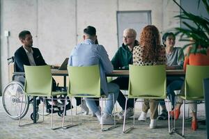 un' diverso gruppo di attività commerciale professionisti, Compreso un persona con un' disabilità, si riunirono a un' moderno ufficio per un' produttivo e compreso incontro. foto