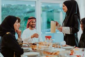 musulmano famiglia avendo iftar cena potabile acqua per rompere festa. mangiare tradizionale cibo durante Ramadan banchettare mese a casa. il islamico halal mangiare e potabile nel moderno casa foto