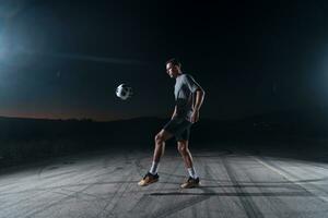 ritratto di un' giovane bello calcio giocatore uomo su un' strada giocando con un' calcio sfera. foto