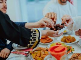 musulmano famiglia avendo iftar cena potabile acqua per rompere festa. mangiare tradizionale cibo durante Ramadan banchettare mese a casa. il islamico halal mangiare e potabile nel moderno casa foto