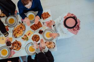 musulmano famiglia avendo iftar cena potabile acqua per rompere festa. mangiare tradizionale cibo durante Ramadan banchettare mese a casa. il islamico halal mangiare e potabile nel moderno casa foto