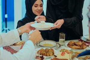 musulmano famiglia avendo iftar cena potabile acqua per rompere festa. mangiare tradizionale cibo durante Ramadan banchettare mese a casa. il islamico halal mangiare e potabile nel moderno casa foto
