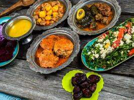 eid mubarak tradizionale Ramadan iftar cena. assortito gustoso cibo nel autentico rustico piatti su di legno blu sfondo. Turco bosniaco cibo carne kebab, Pita, sarma, Klepe, sogan dolma. foto