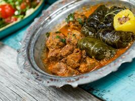 eid mubarak tradizionale Ramadan iftar cena. assortito gustoso cibo nel autentico rustico piatti su di legno blu sfondo. Turco bosniaco cibo carne kebab, Pita, sarma, Klepe, sogan dolma. foto