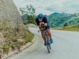 pieno lunghezza ritratto di un attivo triatleta nel abbigliamento sportivo e con un' protettivo casco equitazione un' bicicletta. selettivo messa a fuoco foto