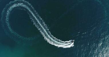 aereo superiore Visualizza di un' bianca piacere barca su un' estate giorno. motoscafo girare ciclo continuo otto su il mare fabbricazione infinito futuro concetto. foto