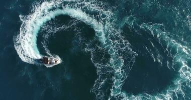 aereo superiore Visualizza di un' bianca piacere barca su un' estate giorno. motoscafo girare ciclo continuo otto su il mare fabbricazione infinito futuro concetto. foto