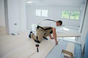 lavoratore installazione nuovo laminato di legno pavimento foto