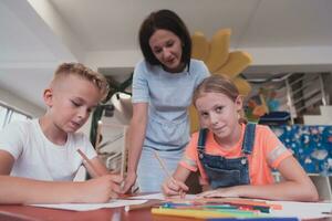 creativo bambini durante un arte classe nel un' asilo nido centro o elementare scuola aula disegno con femmina insegnante. foto