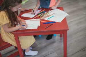 creativo bambini seduta nel un' prescolastico istituzione, disegnare e avere divertimento mentre essi ottenere un formazione scolastica foto