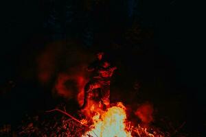 soldato nel azione a notte nel il foresta la zona. notte tempo militare missione salto al di sopra di fuoco foto