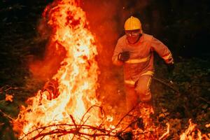pompiere eroe nel azione Pericolo salto al di sopra di fuoco fiamma per salvare e Salva foto