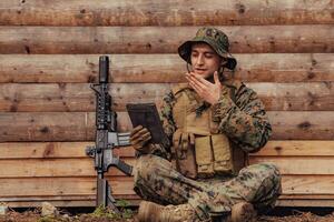 soldato utilizzando tavoletta computer contro vecchio di legno parete nel militare campo per restare nel contatto con amici e famiglia foto