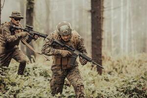 un' gruppo di moderno guerra soldati è combattente un' guerra nel pericoloso a distanza foresta le zone. un' gruppo di soldati è combattente su il nemico linea con moderno Armi. il concetto di guerra e militare conflitti foto