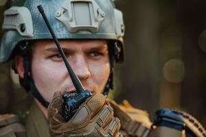moderno guerra soldato comandante ufficiale parlando portatile Radio stazione e dare ordini suddivisione squadra foto
