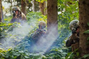 un' gruppo di moderno guerra soldati è combattente un' guerra nel pericoloso a distanza foresta le zone. un' gruppo di soldati è combattente su il nemico linea con moderno Armi. il concetto di guerra e militare conflitti foto