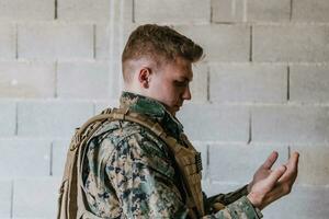 un' musulmano soldato di il speciale forze prega per Dio di raccolta il suo mani e inizia un' preghiera foto