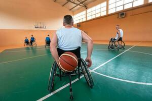 Disabilitato guerra veterani misto gara e età pallacanestro squadre nel sedie a rotelle giocando un' formazione incontro nel un' gli sport Palestra sala. portatori di handicap persone reinserimento e inclusione concetto foto