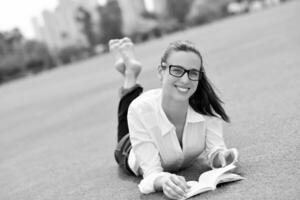 giovane donna che legge un libro nel parco foto