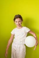 ritratto di un' poco scuola ragazza con varicella, antisettico crema applicato per viso e corpo. giocando con un' bianca Palloncino. Salute cura e medico concetto. verde schermo sfondo. foto