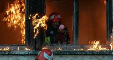 pompiere eroe trasporto bambino ragazza su a partire dal ardente edificio la zona a partire dal fuoco incidente. salvare persone a partire dal pericoloso posto foto