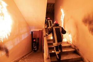 coraggioso vigile del fuoco andando di sopra per Salva e salvare persone nel un' ardente costruzione. Aperto fuoco e fiamma. foto