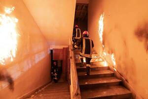 coraggioso vigile del fuoco discende le scale di un' ardente edificio e detiene salvato ragazza nel il suo braccia. Aperto fuoco e uno pompiere nel il sfondo. foto