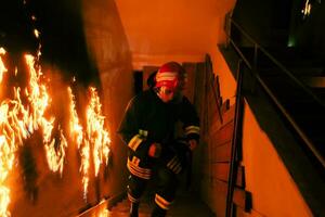 coraggioso vigile del fuoco andando di sopra per Salva e salvare persone nel un' ardente costruzione. Aperto fuoco e fiamma. foto