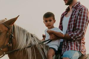 padre e figlio godere equitazione cavalli insieme di il mare. selettivo messa a fuoco foto