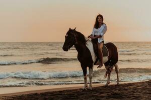 donna nel estate Abiti gode equitazione un' cavallo su un' bellissimo sabbioso spiaggia a tramonto. selettivo messa a fuoco foto