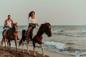 un' amorevole coppia nel estate Abiti equitazione un' cavallo su un' sabbioso spiaggia a tramonto. mare e tramonto nel il sfondo. selettivo messa a fuoco foto