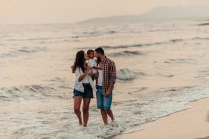 il famiglia gode loro vacanza come essi camminare il sabbioso spiaggia con loro figlio. selettivo messa a fuoco foto