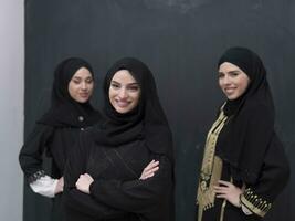 gruppo ritratto di bellissimo musulmano donne nel un' alla moda vestito con hijab isolato su nero sfondo foto