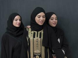 gruppo ritratto di bellissimo musulmano donne nel un' alla moda vestito con hijab isolato su nero sfondo foto