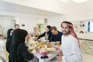 giovane arabo uomo avendo iftar cena con musulmano famiglia mangiare tradizionale cibo durante Ramadan banchettare mese a casa. il islamico halal mangiare e potabile islamico famiglia foto