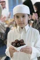 eid mubarak musulmano famiglia avendo iftar cena poco ragazzo Tenere un' piatto pieno di dolce date per rompere festa. mangiare tradizionale cibo durante Ramadan banchettare mese a casa. il islamico halal mangiare foto