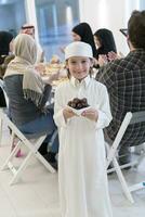 eid mubarak musulmano famiglia avendo iftar cena poco ragazzo Tenere un' piatto pieno di dolce date per rompere festa. mangiare tradizionale cibo durante Ramadan banchettare mese a casa. il islamico halal mangiare foto