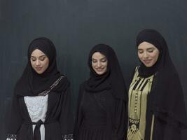 gruppo ritratto di bellissimo musulmano donne nel un' alla moda vestito con hijab isolato su nero sfondo foto