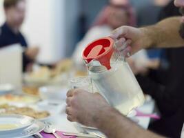 eid mubarak musulmano famiglia avendo iftar cena potabile acqua per rompere festa. mangiare tradizionale cibo durante Ramadan banchettare mese a casa. il islamico halal mangiare e potabile a moderno occidentale isla foto