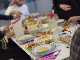 eid mubarak musulmano famiglia avendo iftar cena potabile acqua per rompere festa. mangiare tradizionale cibo durante Ramadan banchettare mese a casa. il islamico halal mangiare e potabile a moderno occidentale isla foto