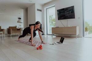 giovane bellissimo femmina esercizio, allungamento e praticando yoga con allenatore attraverso video chiamata conferenza nel luminosa soleggiato Casa. salutare stile di vita, benessere e consapevolezza concetto. foto