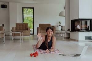 giovane bellissimo femmina esercizio, allungamento e praticando yoga con allenatore attraverso video chiamata conferenza nel luminosa soleggiato soffitta appartamento. salutare stile di vita, benessere e consapevolezza concetto. foto