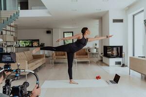 dietro a il scena. foto di un' cineoperatore registrazione un' donna fare yoga esercizi a un in linea formazione mentre utilizzando e Guardando un' il computer portatile