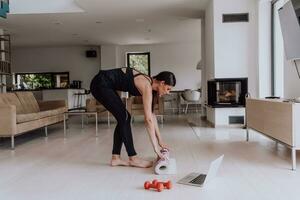 un' giovane donna nel gli sport Abiti preparazione gli sport attrezzatura per in linea formazione nel sua vivente camera foto